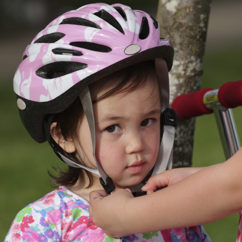 young girl having her helmet put on